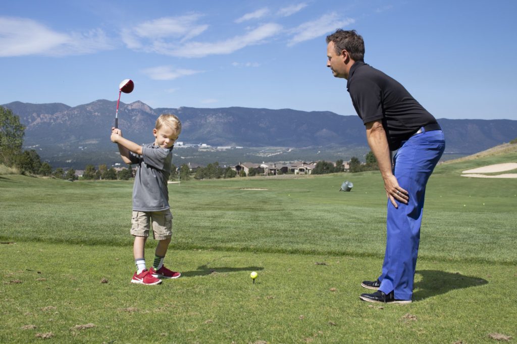 Garrett with young golfer during lesson on golf course