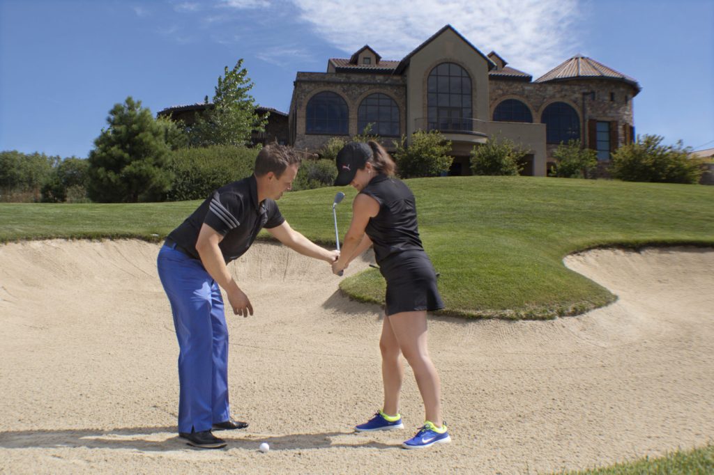 Golfer receiving instruction in bunker